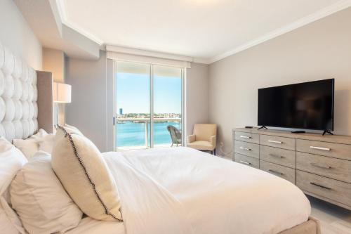 a white bedroom with a large bed and a television at Golden Bay 808 in Miami Beach