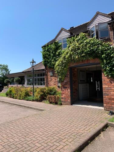a brick house with a garage with ivy on it at The Punchbowl Lapworth in Solihull