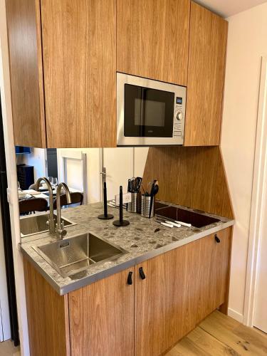 une cuisine avec un évier et un micro-ondes dans l'établissement Ecrin Alpin hyper centre d'Auron, à Saint-Étienne-de-Tinée
