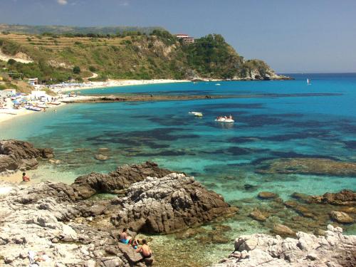 a beach with a group of people in the water at Residence Hotel Felix in Ricadi
