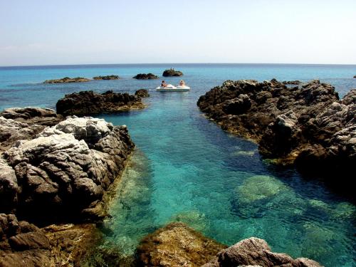 two people in a boat in the water near rocks at Residence Hotel Felix in Ricadi