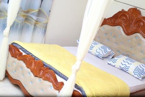 un letto con struttura in legno e cuscini sopra di pettan Appartment a Kampala