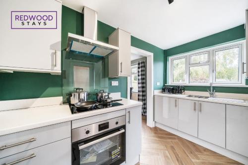 una cocina con armarios blancos y paredes verdes en 2 Bed 1 Bath House, Perfect for Corporate, Contractors & Families x2 FREE Parking, Garden, Netflix By REDWOOD STAYS en Alton