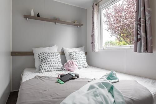 1 dormitorio con cama con libro y ventana en Bontempo Village, en Piriac-sur-Mer