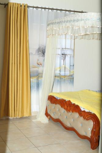 1 dormitorio con cama con dosel y cortina amarilla en pettan Appartment, en Kampala
