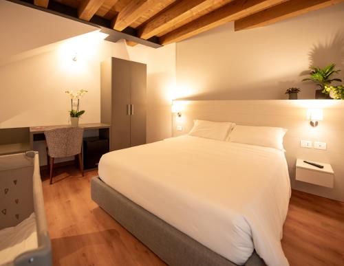 Schlafzimmer mit einem großen weißen Bett und einem Schreibtisch in der Unterkunft Agri-alloggio le Poscole Al Canton in Castelgomberto