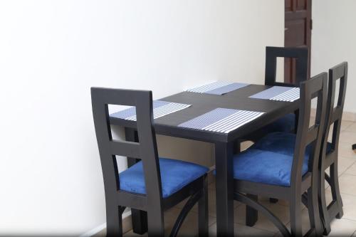 ein schwarzer Tisch mit zwei Stühlen, einem Tisch und einem Tisch mit einem Stuhl in der Unterkunft pettan Appartment in Kampala