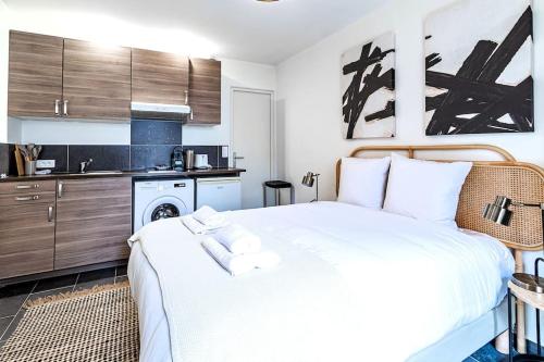 Cet appartement comprend une chambre avec un lit blanc et une cuisine. dans l'établissement Studio équipé à 5 minutes de Paris - Montreuil -II, à Montreuil