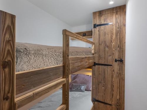 - une chambre avec des lits superposés et une porte en bois dans l'établissement Appartement rénové, ski aux pieds, cœur de Val Thorens - FR-1-640-34, à Val Thorens