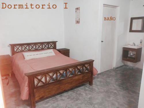 a bedroom with a wooden bed and a door to a bathroom at Casa de Campo Atenea in Santiago del Estero