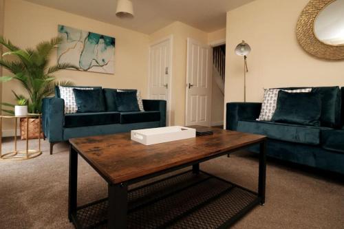 a living room with blue couches and a coffee table at Modern 4 Bed House with Parking in Swadlincote
