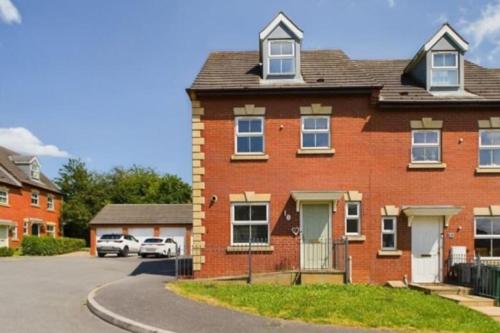 a red brick house with a car parked in a driveway at Modern 4 Bed House with Parking in Swadlincote