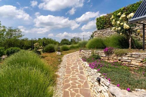 un jardín con un camino de piedra y flores en Casa Sara and Sasha near Motovun with private pool - Truffle Paradise en Oprtalj