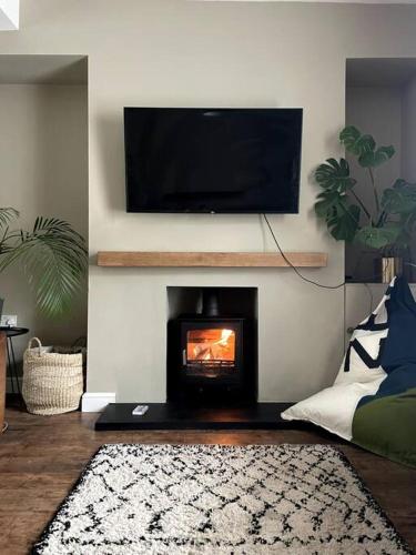 a living room with a fireplace with a tv above it at Home in West by the Sea in Llanelli