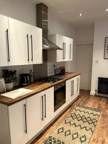 a kitchen with white cabinets and a wooden counter top at Home in West by the Sea in Llanelli