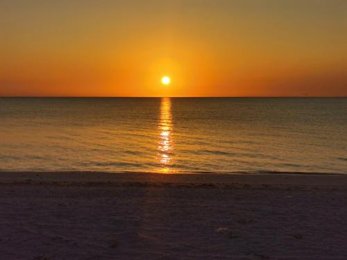 a sunset on the beach with the sun setting at Hotel Manglares Cabaña Pelicano in Celestún