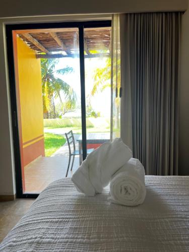 a bed with a roll of towels on top of it at Hotel Manglares Cabaña Pelicano in Celestún