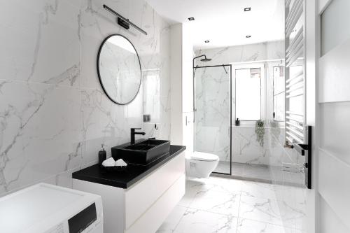a white bathroom with a sink and a mirror at Apartament Starołęcka Warta Residence PARKING included in Poznań