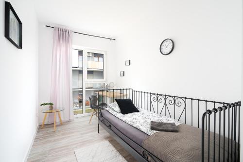 a bedroom with a bed and a clock on the wall at Apartament Starołęcka Warta Residence PARKING included in Poznań