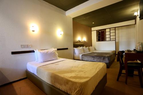 a hotel room with two beds and a desk at Fata Hotel by Project Borneo in Kuching