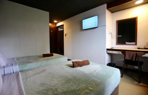 Fata Hotel by Project Borneo في كوتشينغ: غرفة نوم بسريرين ومكتب وتلفزيون