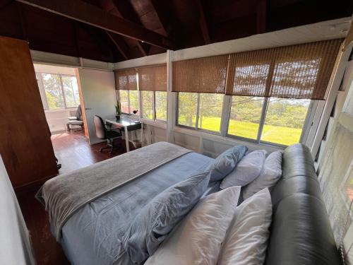 a bedroom with a bed and a couch and windows at La Dama de los vientos in Cerro Azul