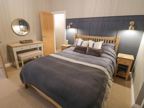a bedroom with a large bed with a blue headboard at Dazie Cottage in Broadway