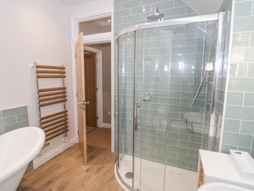 a bathroom with a glass shower with a sink at Dazie Cottage in Broadway