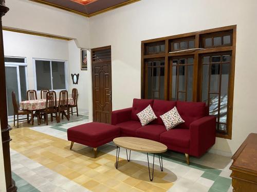 a living room with a red couch and a table at Nawasena Guesthouse Jogja in Kalasan