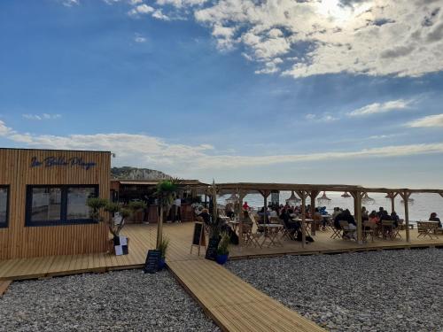 a restaurant on the beach with people sitting on a deck at "Le JUGUILI" 46m2 en front de Mer - 4 personnes - animaux OK - Entièrement rénové - Haut de gamme - wifi in Mers-les-Bains