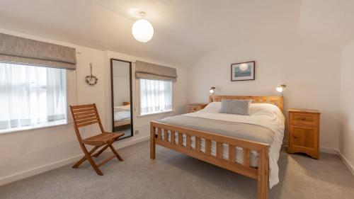 a bedroom with a bed and a chair in it at Puddle Cottage in Southwold