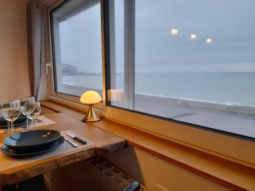 a table with wine glasses and a window at "Le JUGUILI" 46m2 en front de Mer - 4 personnes - animaux OK - Entièrement rénové - Haut de gamme - wifi in Mers-les-Bains