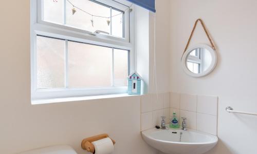 a white bathroom with a sink and a window at Puddle Cottage in Southwold
