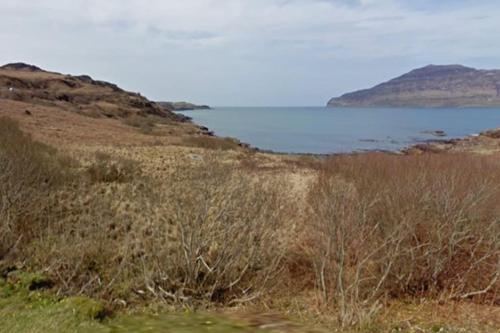 a field of grass with a body of water at Ormsaig Byre in Beach