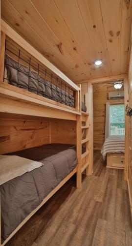 a bedroom with two bunk beds in a log cabin at Lena Cabin Wooded Tiny Cabin - Hot Tub in Chattanooga