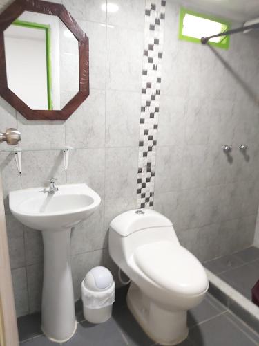 a bathroom with a white toilet and a sink at Hostal y Camping Los Girasoles in Salento