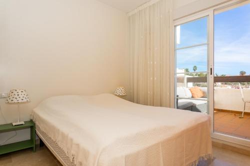 a white bedroom with a bed and a large window at Penthouse Apartment in Benalmadena in Benalmádena
