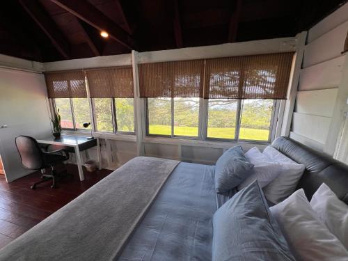 a bedroom with a large bed with a couch and windows at La Dama de los vientos in Cerro Azul