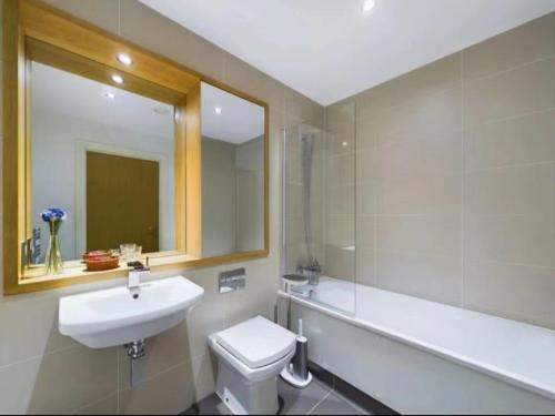 a bathroom with a sink and a toilet and a mirror at Homestay Room in Apartment with Stunning Thames River View in London