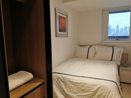 a small bedroom with a bed and a window at Homestay Room in Apartment with Stunning Thames River View in London