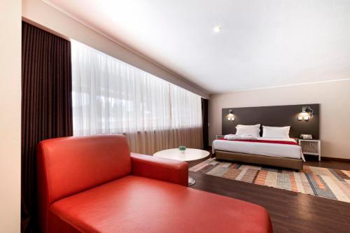 a bedroom with a bed and a red chair at Hotel Amadeos - Matosinhos - Porto in Matosinhos