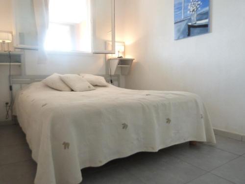 Un dormitorio con una cama con una manta blanca. en PCOGBLAN - Golfe de Saint-Tropez - T2 avec piscine vue marina, en Cogolin