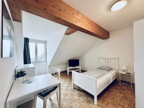 1 dormitorio con cama blanca y escritorio en Monteurzimmer ZIMMERzuVERMIETEN in Flumenthal Solothurn, en Attiswil