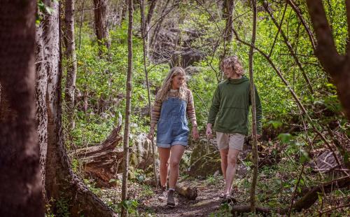 a man and a young girl walking down a trail in the woods at Papa Cabin Tiny Log Home Comfort In Rustic Bliss in Chattanooga
