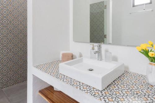 a bathroom with a white sink and a vase of flowers at Casa Monarcas - María Teresa (with AC) in Guadalajara