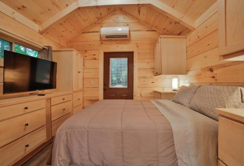 a bedroom in a log cabin with a bed and a tv at Nana Cabin Tiny Log Home Comfort In Rustic Bliss in Chattanooga