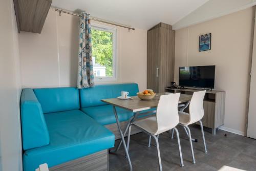 un salon avec un canapé bleu, une table et des chaises dans l'établissement Camping les falaises de Toussaint, à Toussaint