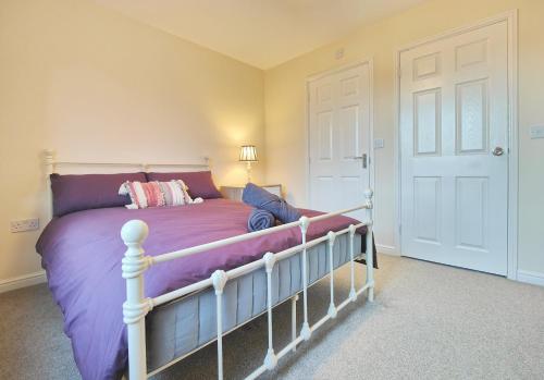 ein Schlafzimmer mit einem großen Bett mit violetter Bettwäsche in der Unterkunft The Bushmoor - Spacious Holiday Townhouse 10 Minutes to City Centre Free Parking in Manchester