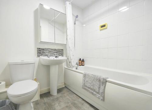 Baño blanco con aseo y lavamanos en The Bushmoor - Spacious Holiday Townhouse 10 Minutes to City Centre Free Parking, en Mánchester