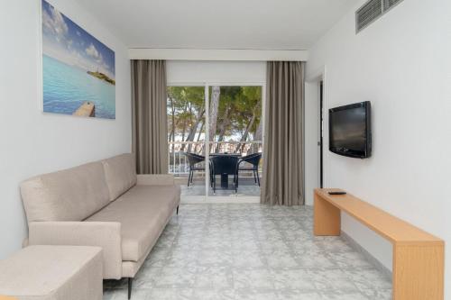 a living room with a couch and a television at Apartamentos Ferrer Lime Playa de Alcudia in Port d'Alcudia
